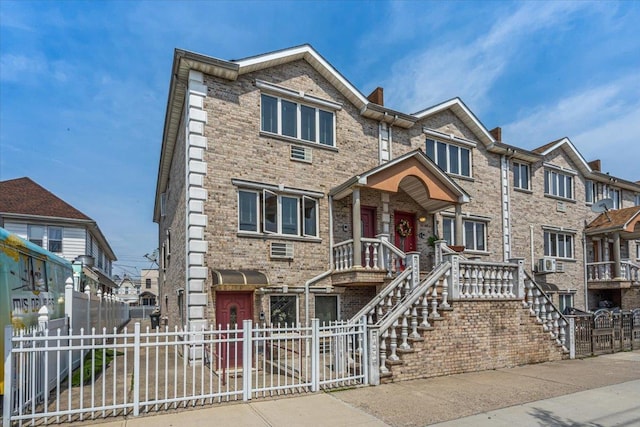 6147 Grand Ave, Maspeth, NY 11378 - townhome / multi-family property featuring a fenced front yard, covered porch, brick siding, a residential view, and stairs