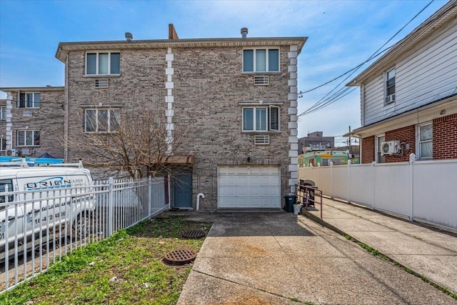 6147 Grand Ave, Maspeth, NY 11378 - back of property with brick siding, fence, concrete driveway, and an attached garage