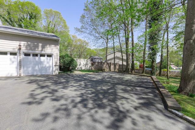 exterior space with fence, driveway, and a garage