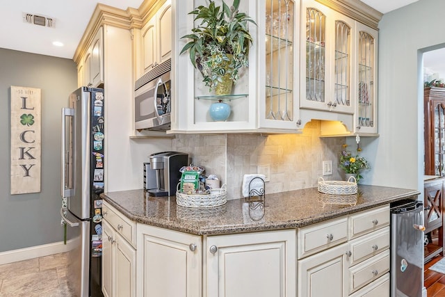 kitchen with visible vents, decorative backsplash, baseboards, dark stone counters, and appliances with stainless steel finishes