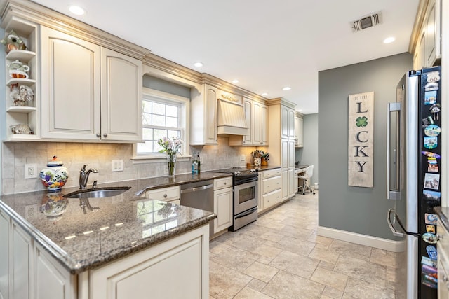 kitchen featuring appliances with stainless steel finishes, a sink, a peninsula, baseboards, and tasteful backsplash