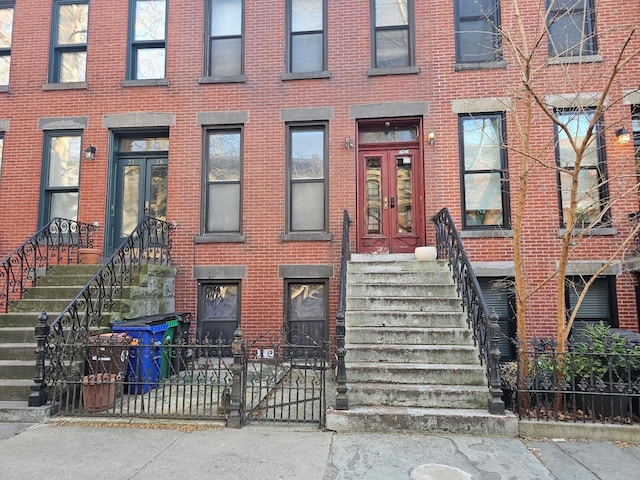 property entrance featuring brick siding, french doors, and fence