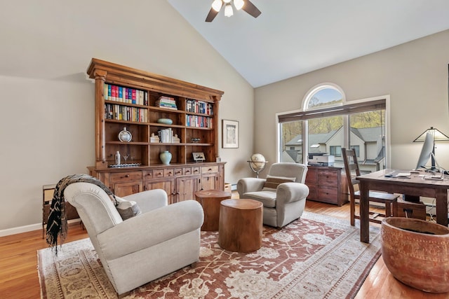 living area with light wood finished floors, ceiling fan, high vaulted ceiling, and baseboards