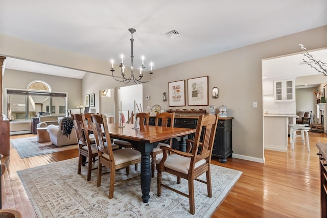 dining space with an inviting chandelier, visible vents, light wood-type flooring, and baseboards