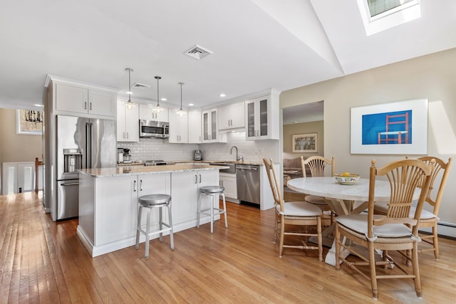 kitchen with visible vents, light wood-type flooring, appliances with stainless steel finishes, and a kitchen island