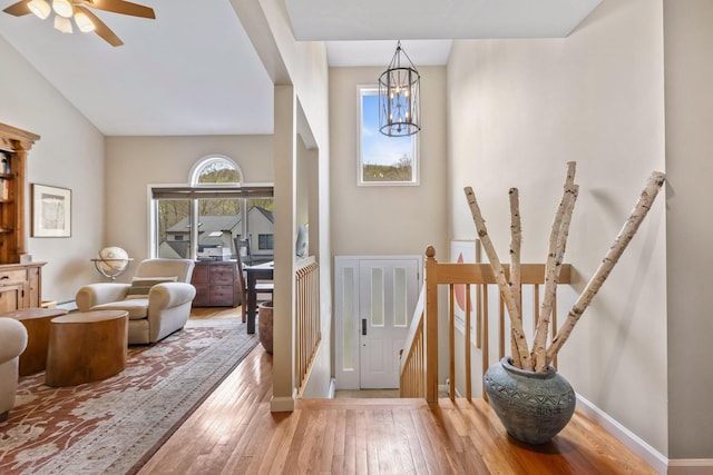 entrance foyer with baseboards, ceiling fan with notable chandelier, wood-type flooring, and a baseboard radiator