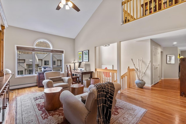 living room with a baseboard heating unit, baseboards, wood finished floors, a ceiling fan, and high vaulted ceiling