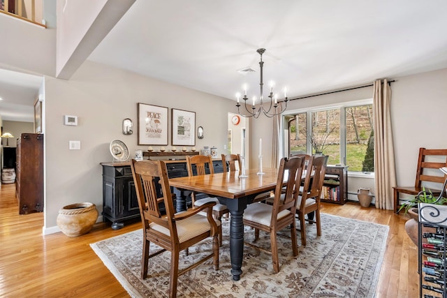 dining area with light wood finished floors, a notable chandelier, and baseboards