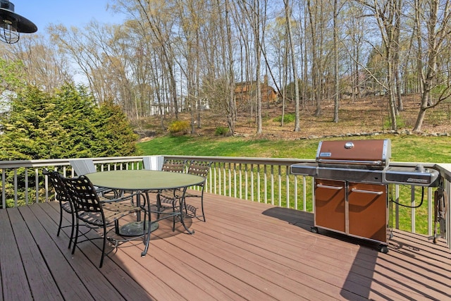 deck featuring a lawn, outdoor dining space, and a grill