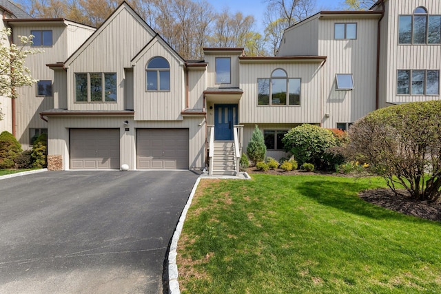 multi unit property with a front lawn, an attached garage, and aphalt driveway