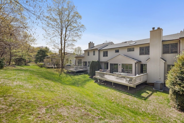 rear view of house featuring a chimney, a deck, a yard, and central air condition unit