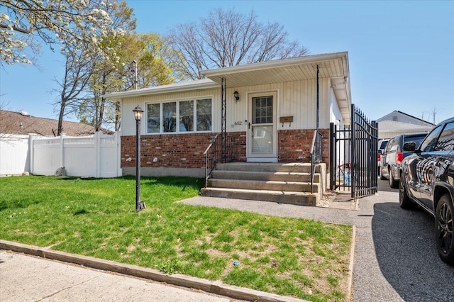 bungalow-style house with fence, a front yard, and brick siding