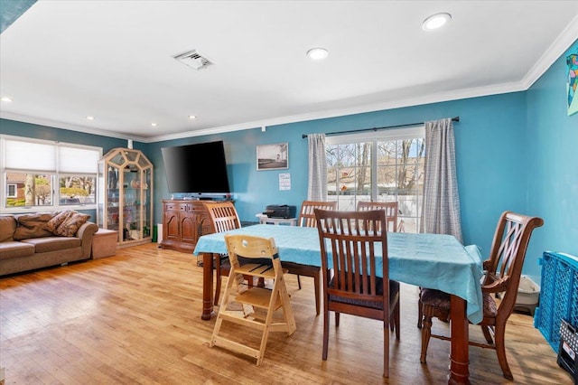dining area featuring light wood-style flooring, a healthy amount of sunlight, crown molding, and visible vents