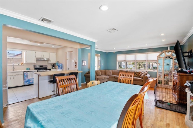 dining area featuring visible vents, ornamental molding, and light wood-style floors