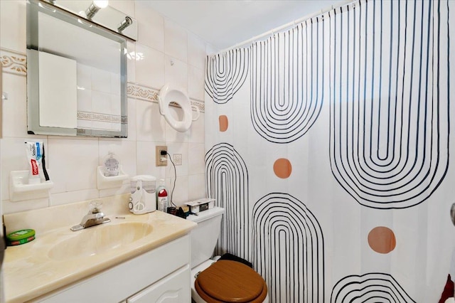 bathroom featuring a shower, toilet, vanity, and tile walls