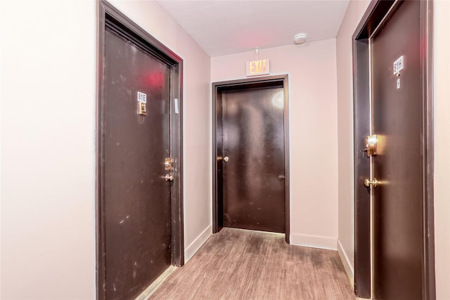 corridor with baseboards and light wood-style floors