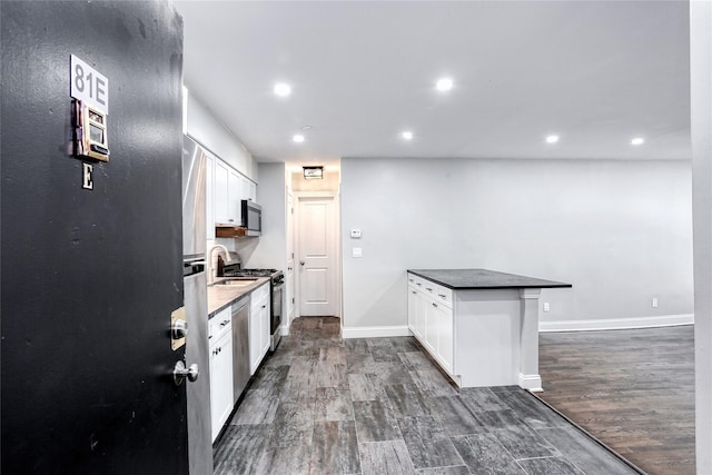 kitchen with a peninsula, appliances with stainless steel finishes, baseboards, and dark wood-style flooring