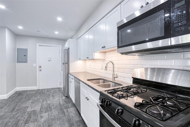 kitchen featuring a sink, decorative backsplash, electric panel, white cabinets, and appliances with stainless steel finishes