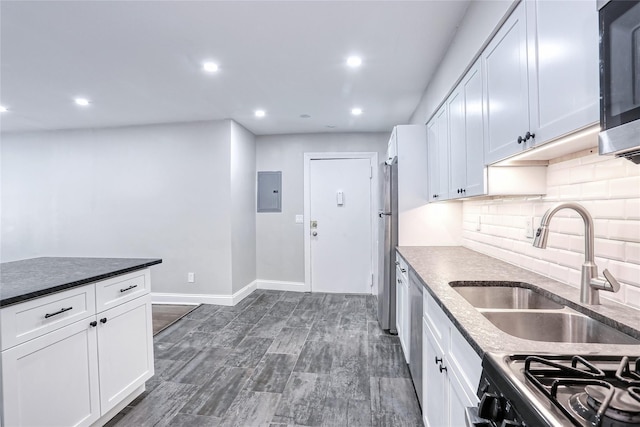 kitchen with a sink, black range with gas cooktop, white cabinetry, and tasteful backsplash