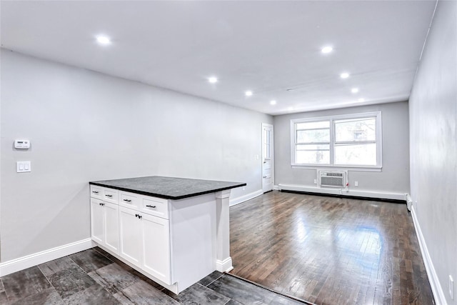 kitchen with dark wood-style floors, dark countertops, baseboards, a peninsula, and white cabinetry