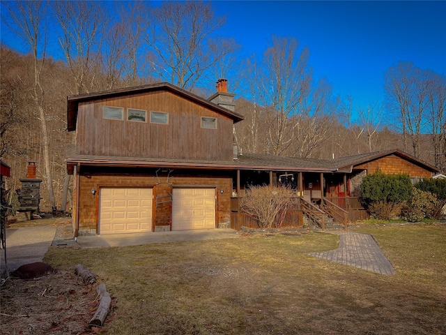 view of front of property featuring a chimney, driveway, an attached garage, a porch, and a front yard
