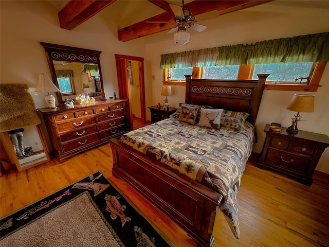 bedroom with a ceiling fan, beamed ceiling, and light wood-type flooring