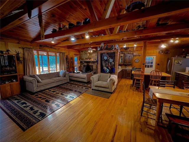 living room with wood ceiling, light wood-style flooring, wooden walls, and a stone fireplace