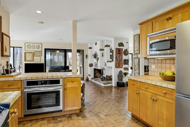 20 Schoolhouse Rd, Waccabuc, NY 10597 - kitchen featuring tile counters, brick floor, tasteful backsplash, and appliances with stainless steel finishes