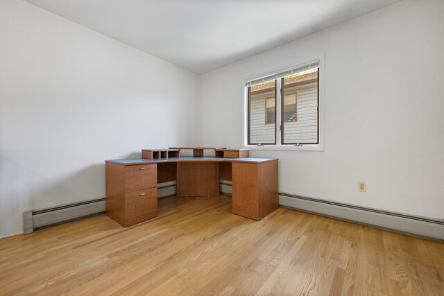 unfurnished office with light wood-style floors, a baseboard heating unit, and baseboard heating