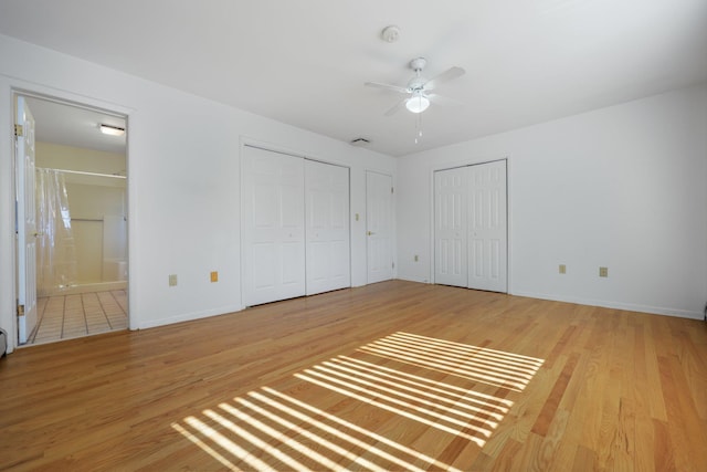 unfurnished bedroom featuring a ceiling fan, baseboards, two closets, connected bathroom, and light wood-style floors