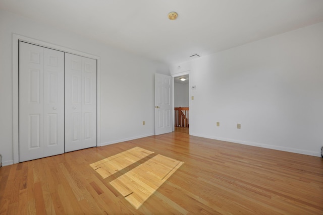 unfurnished bedroom with baseboards, light wood-style flooring, and a closet
