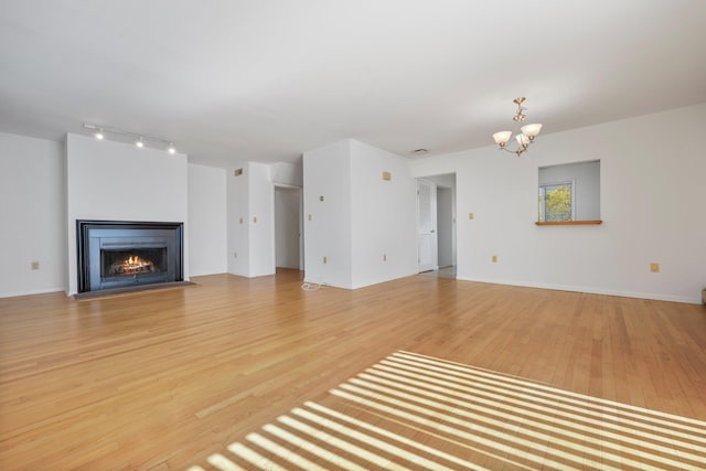 81 Pemberwick Rd Unit A, Greenwich, CT 06831 - unfurnished living room with a chandelier, light wood finished floors, a fireplace with flush hearth, and track lighting