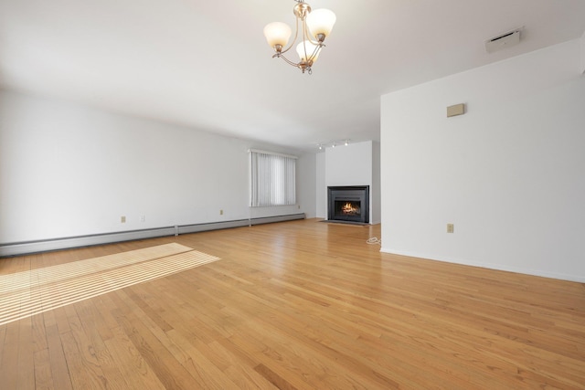 81 Pemberwick Rd Unit A, Greenwich, CT 06831 - unfurnished living room featuring rail lighting, light wood-type flooring, a chandelier, a baseboard radiator, and a lit fireplace