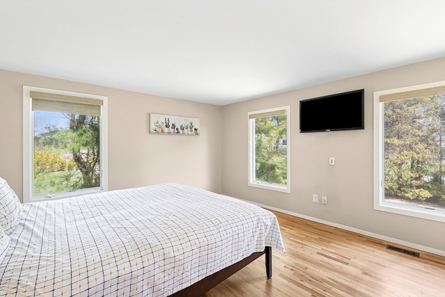 bedroom featuring visible vents, light wood-style flooring, baseboards, and multiple windows