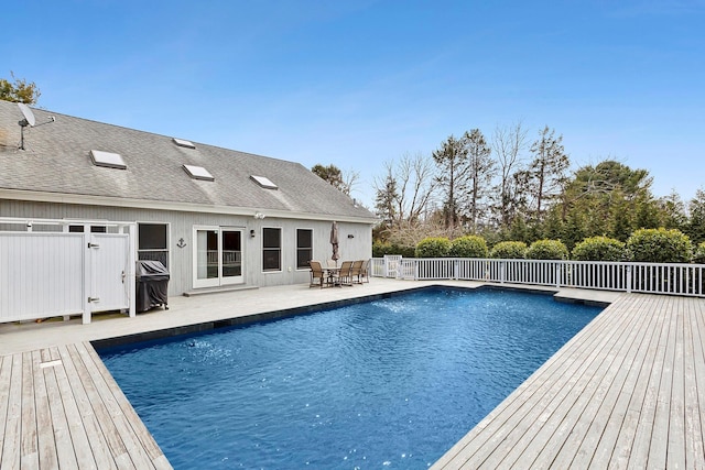 view of swimming pool featuring a wooden deck, a fenced in pool, a patio area, and fence