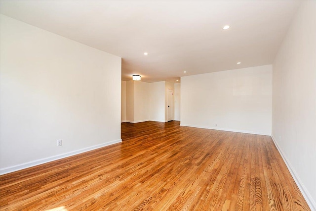 empty room with light wood finished floors, recessed lighting, and baseboards