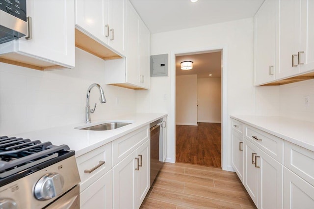 kitchen with a sink, electric panel, light wood finished floors, decorative backsplash, and light countertops