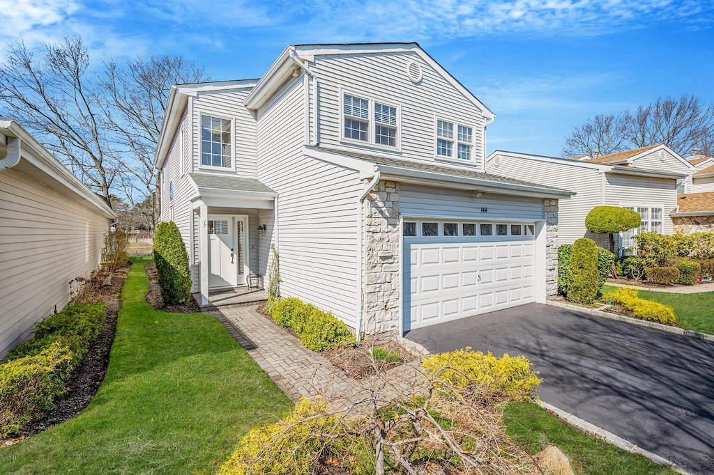 view of front facade with an attached garage, driveway, and stone siding