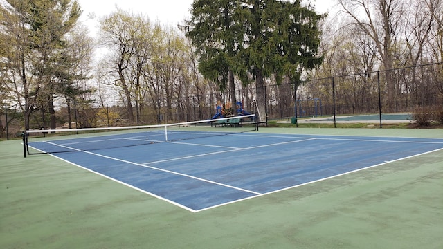 view of tennis court with community basketball court and fence