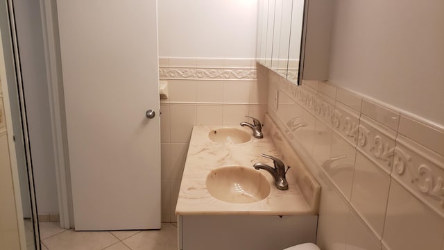 bathroom featuring double vanity, tile walls, tile patterned flooring, and a sink