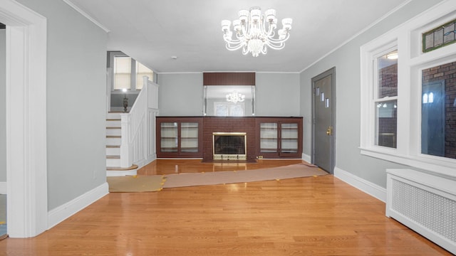 9920 196th St, Hollis, NY 11423 - unfurnished living room featuring radiator, stairway, a chandelier, a fireplace, and ornamental molding
