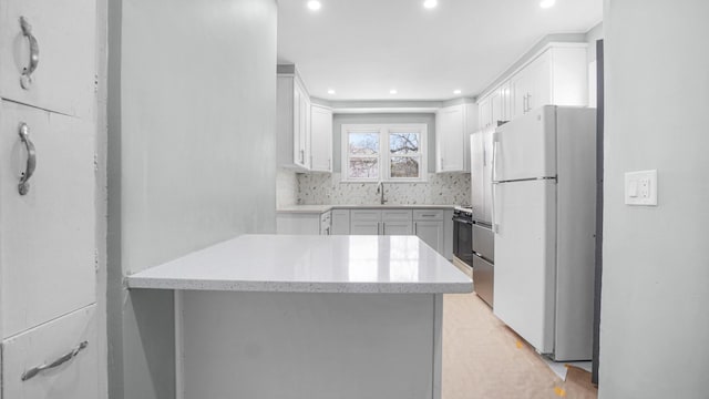 9920 196th St, Hollis, NY 11423 - kitchen with recessed lighting, a sink, a peninsula, white cabinetry, and freestanding refrigerator