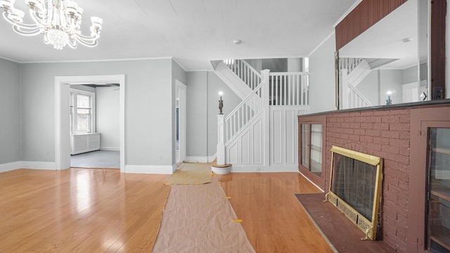 9920 196th St, Hollis, NY 11423 - unfurnished living room with a fireplace, a notable chandelier, stairs, baseboards, and wood finished floors