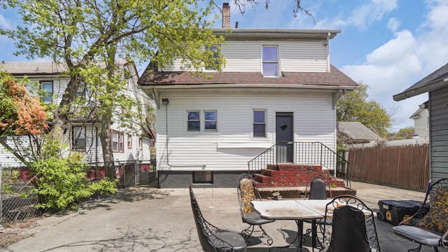 9920 196th St, Hollis, NY 11423 - back of house with fence, roof with shingles, a chimney, and a patio area