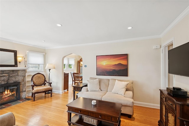 living area featuring arched walkways, light wood-style flooring, and ornamental molding
