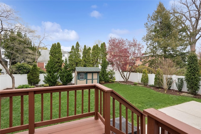 wooden terrace with a fenced backyard, an outdoor structure, a storage shed, and a yard
