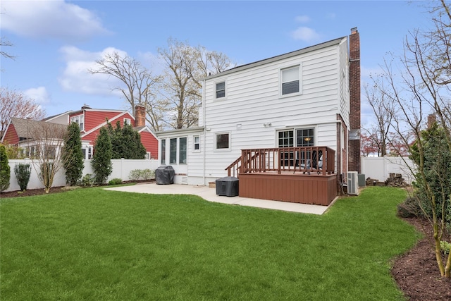 back of house featuring a chimney, a fenced backyard, a patio, a lawn, and a deck