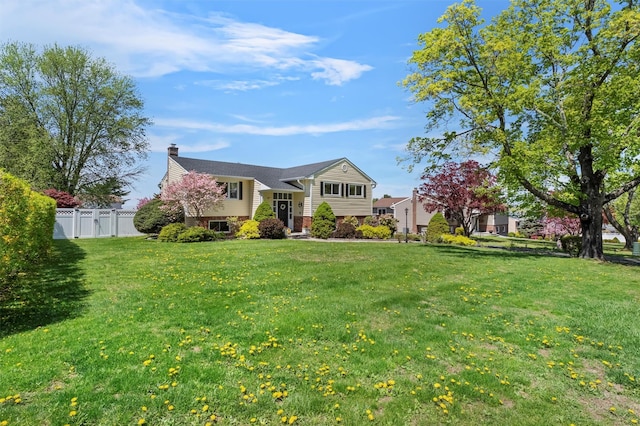 view of front facade featuring fence, a chimney, a front lawn, and brick siding