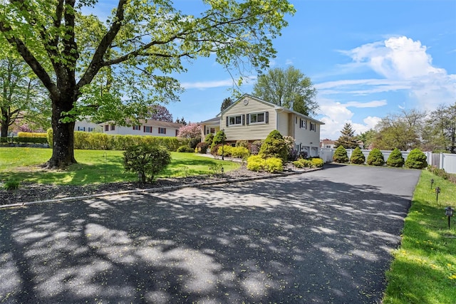 view of front of property with fence, a front lawn, and aphalt driveway