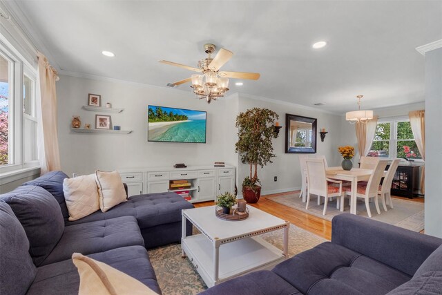 living room featuring recessed lighting, ornamental molding, light wood-style flooring, and ceiling fan with notable chandelier